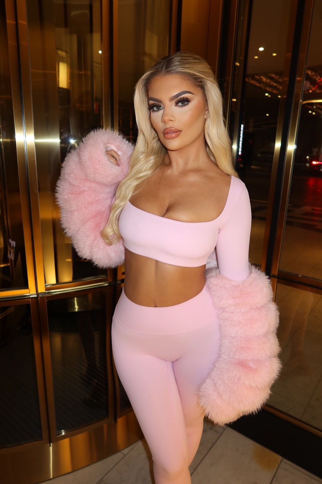 GLAMORZ baby pink crop top and leggings set featuring long sleeves with voluminous faux fur cuffs on a blonde model.