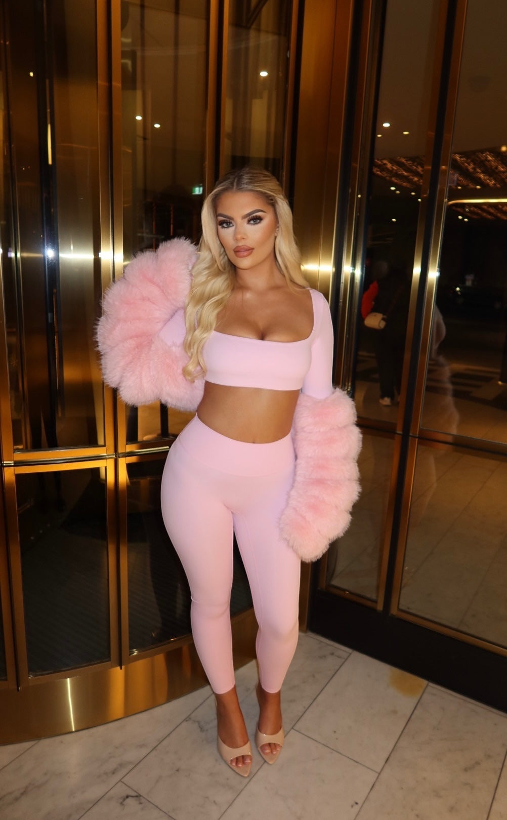 GLAMORZ baby pink two-piece set featuring a cropped top, leggings, and detachable faux fur sleeves on a blonde model.