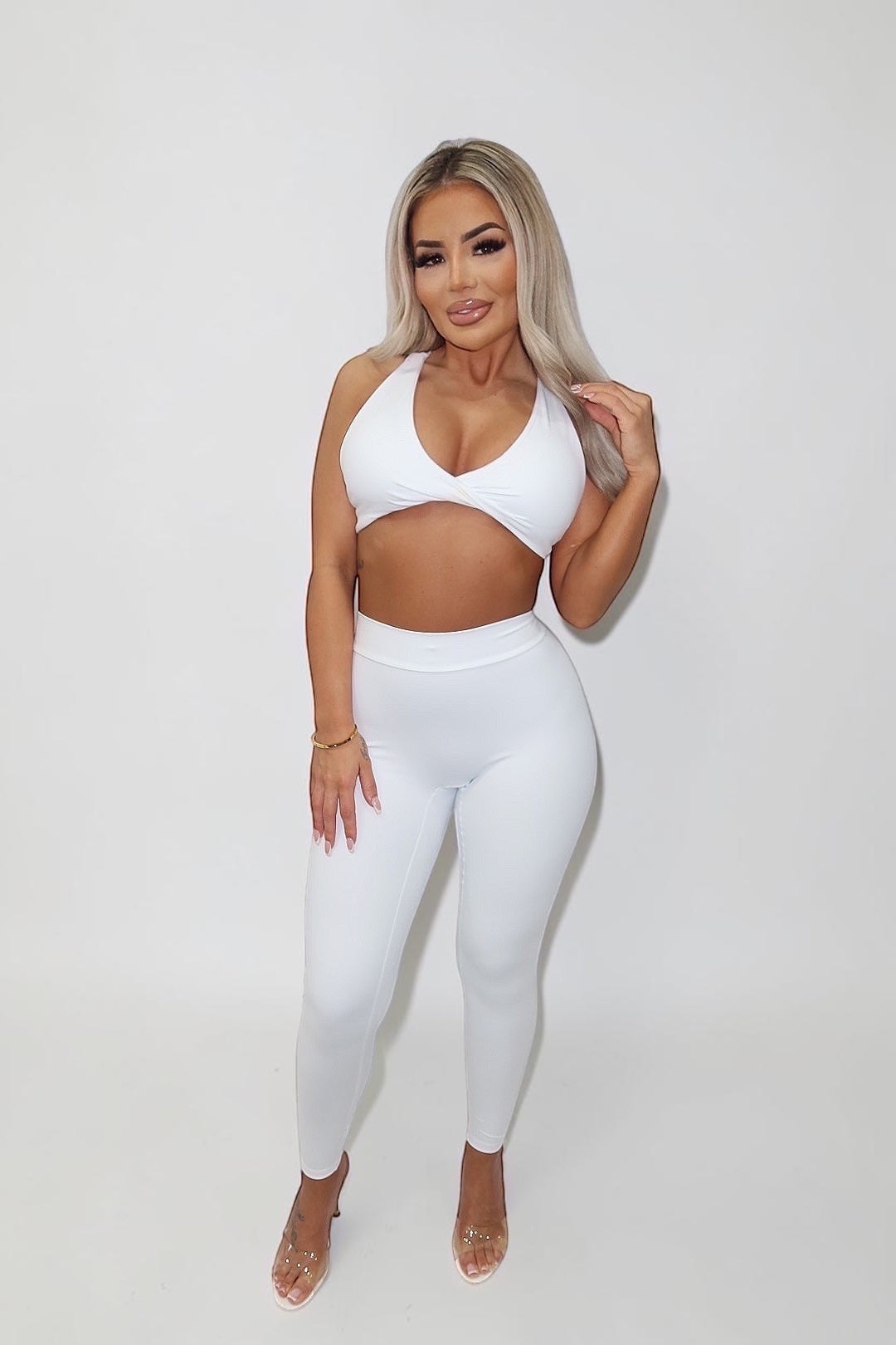 GLAMORZ white BBL bra top with a twisted front design worn by a blonde model with matching white leggings